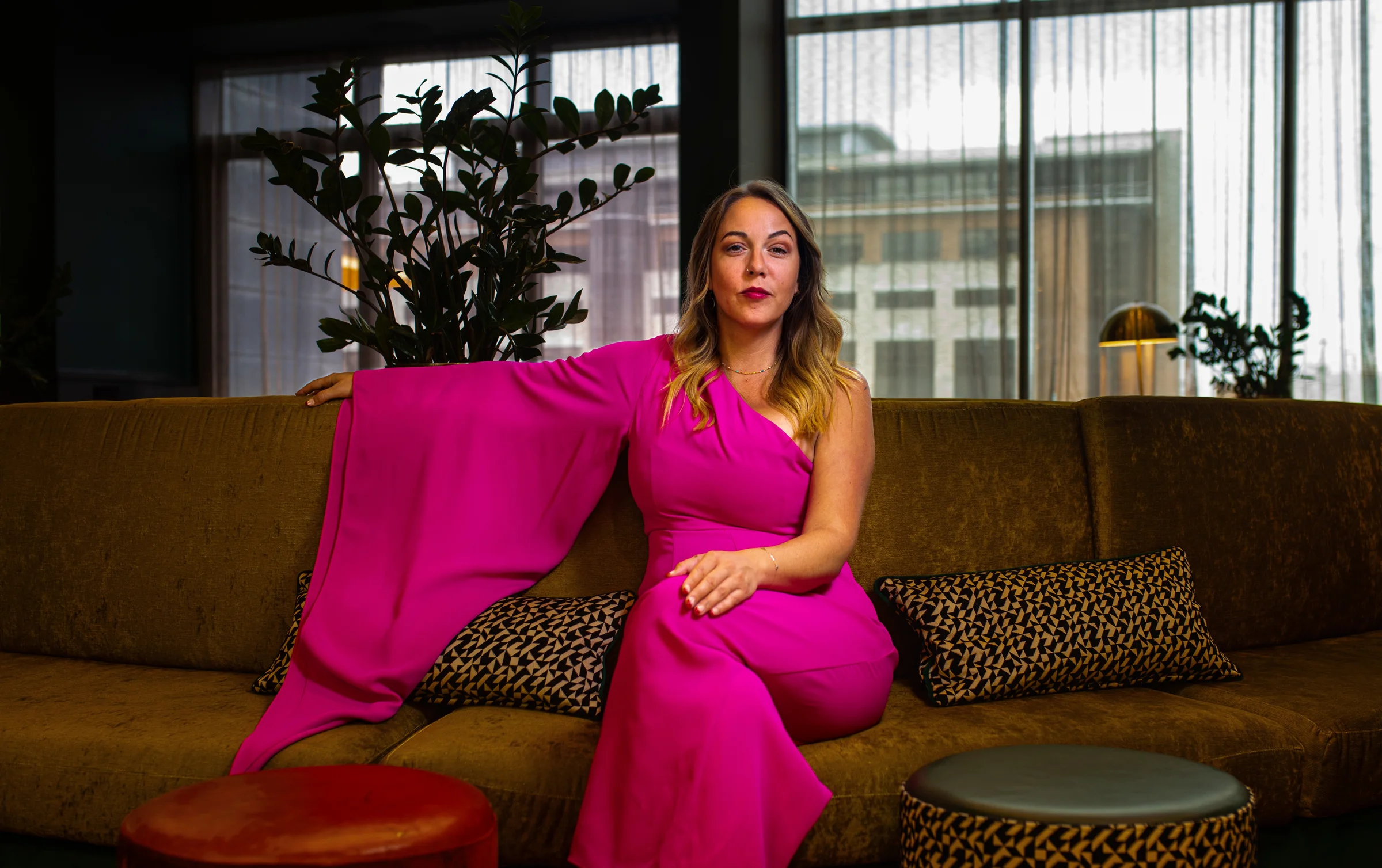 Beth seated in a vivid pink jumpsuit