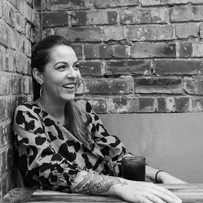 Beth seated beside a brick wall