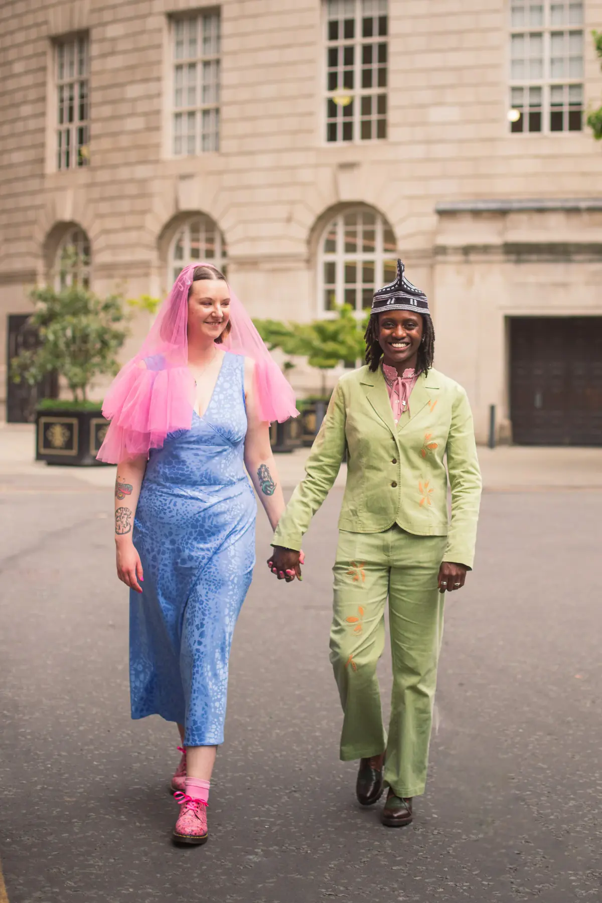 Hayley and Ngwafu walking together in colourful wedding outfits