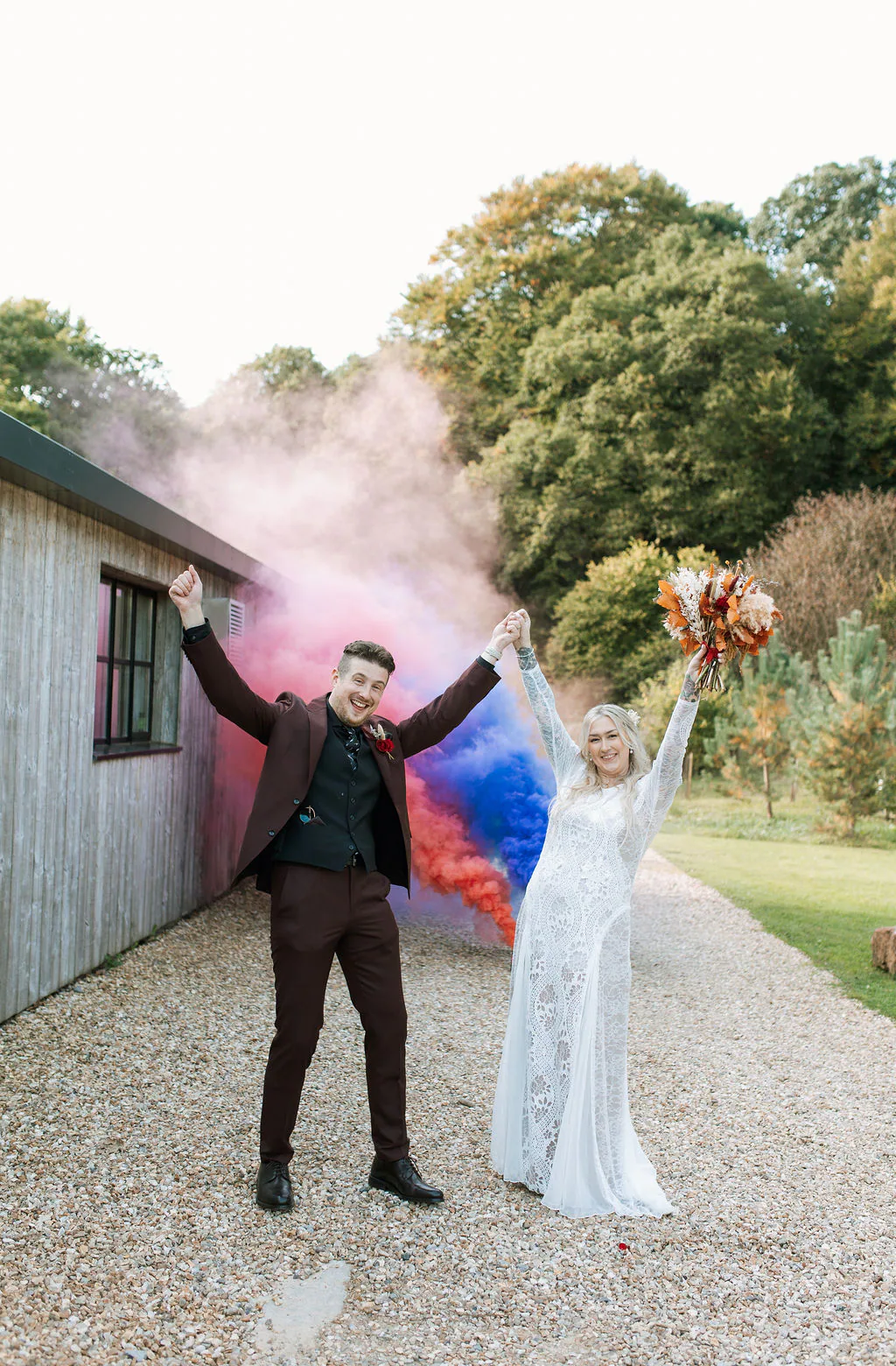 Jess and Ed celebrating together through clouds of colourful smoke