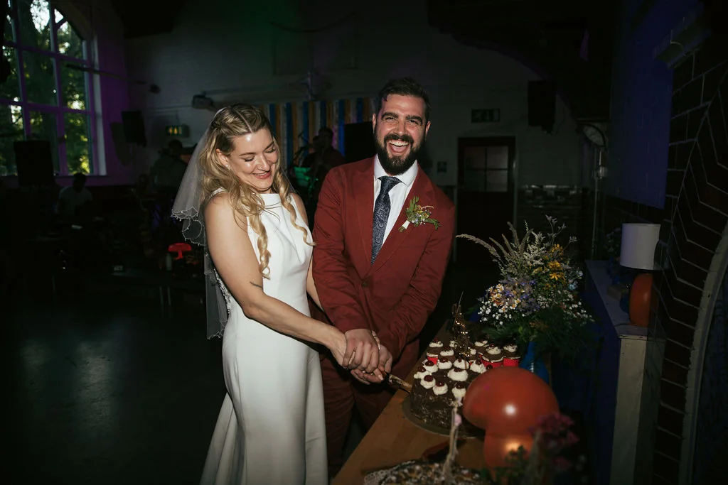 Mark and Jules laughing together as they cut their wedding cake