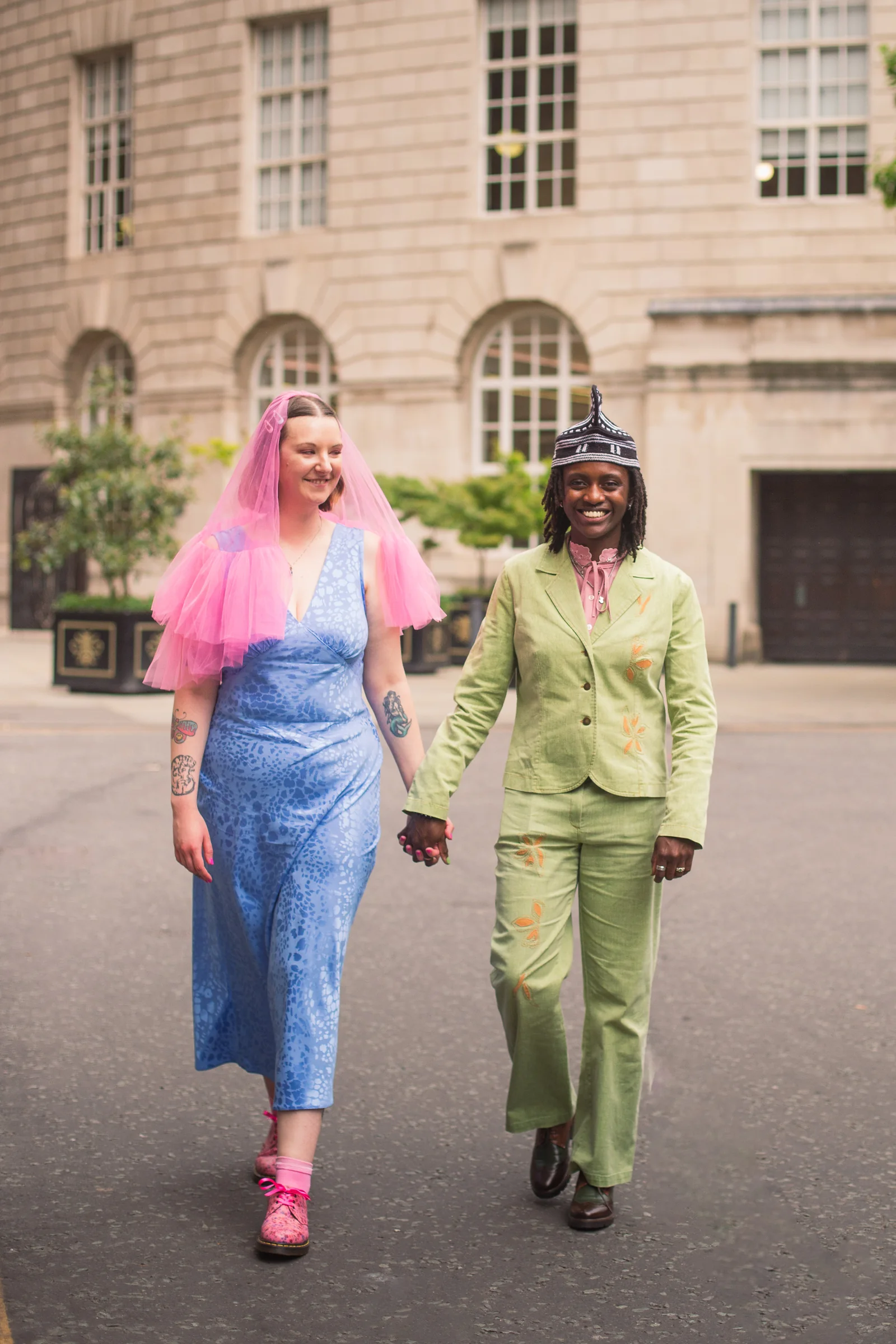 A newly married couple walking hand in hand in colourful wedding outfits