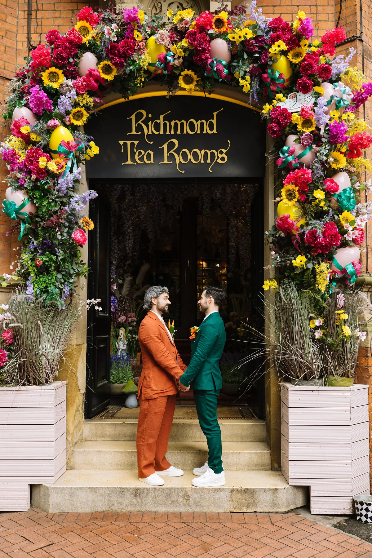 Two grooms beneath the richly decorated Richmond Tea Rooms entrance